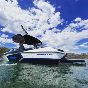 Malibu Wakesetter wake boat floating on calm water under a bright blue sky.